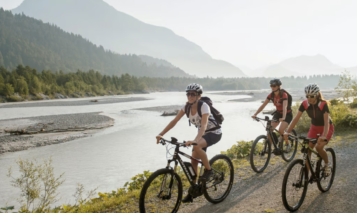 Drei Radfahrer am Lech in der Tiroler Berglandschaft
